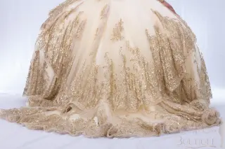 Gold quinceañera dress with sweetheart neckline, sheer long sleeves, and a voluminous ball gown skirt with lace appliqués -3